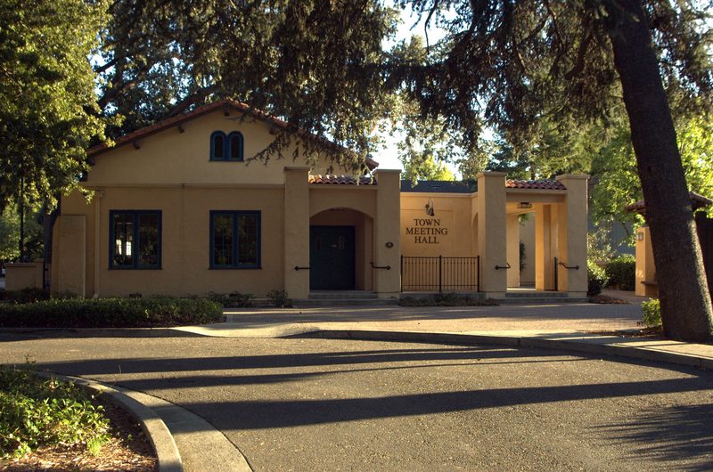 The mission-style Danville Town Meeting Hall building framed by trees.